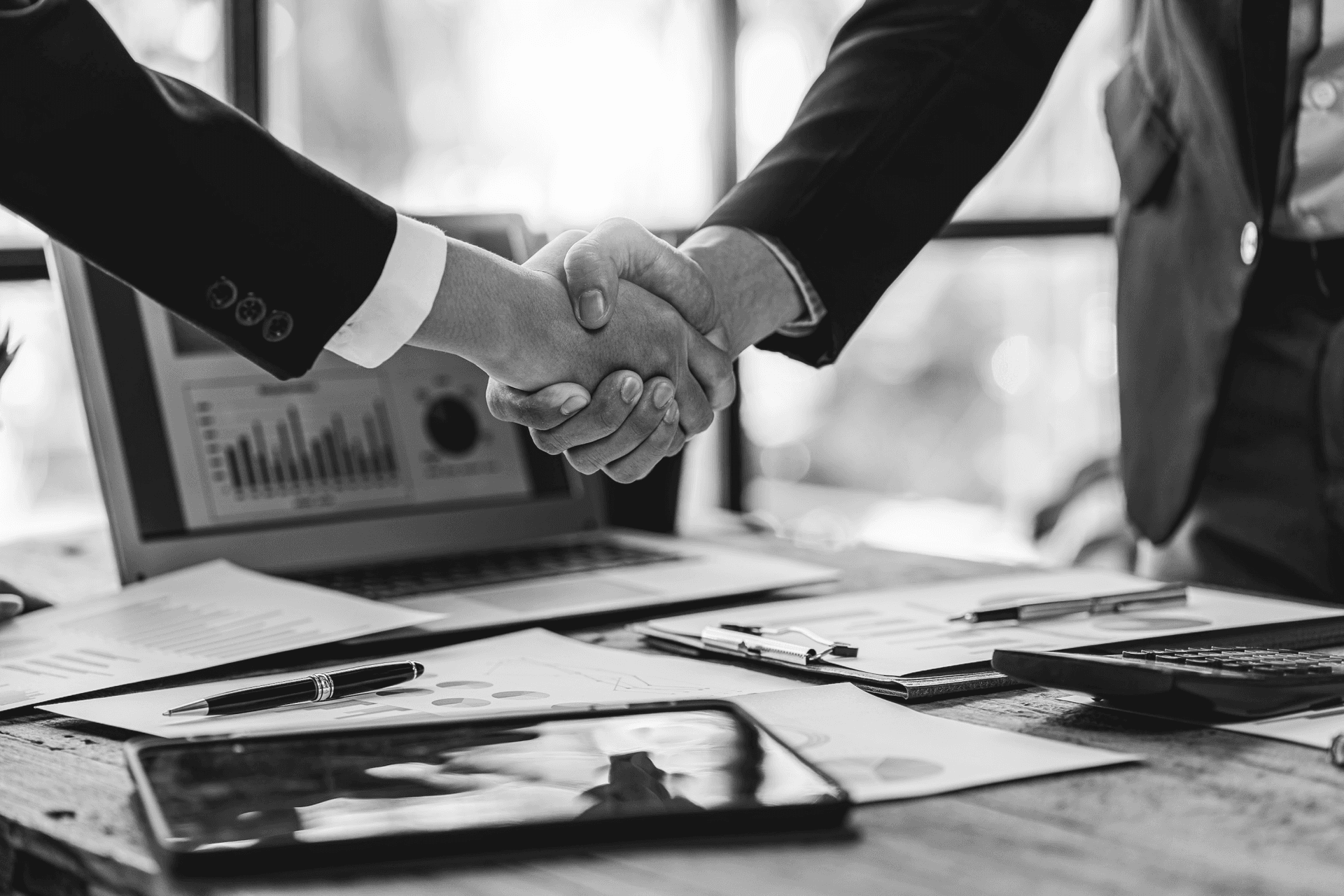 A pair of arms in suits shake hands.