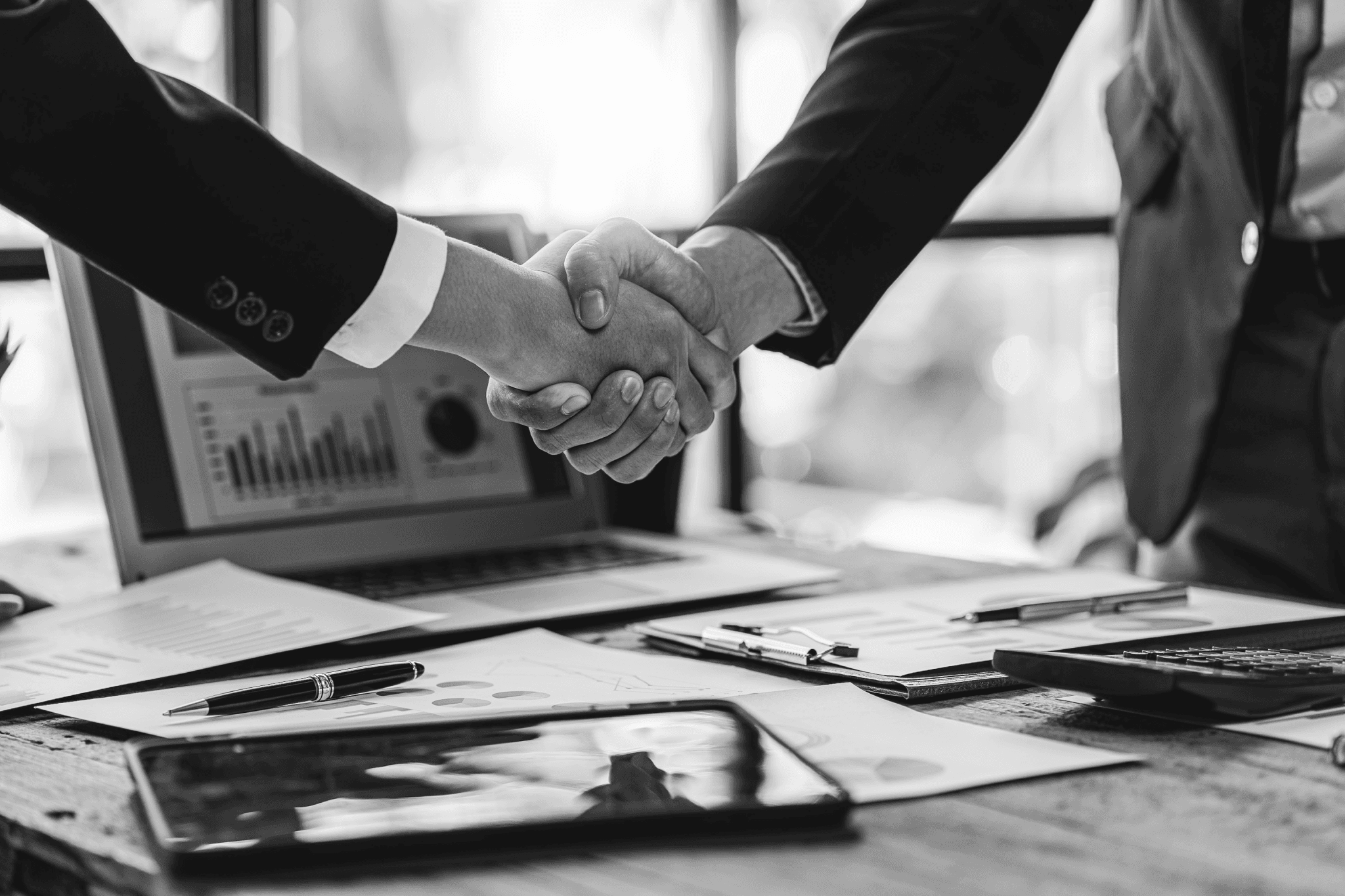 A pair of arms in suits shake hands.